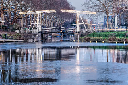Utrecht, The Netherlands, January 21, 2019: illuminated drawbridge across Leidsche Rijn canal, reflecting in the partly frozen water surfceのeditorial素材
