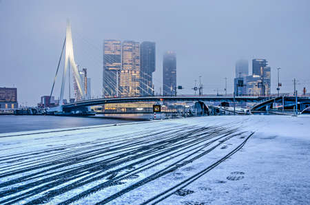 Rotterdam, The Netherlands, February 1, 2019: Bicycle trails in freshly fallen snow on a cold winter morning with the southbank highrise and Erasmus bridge in the backgroundのeditorial素材