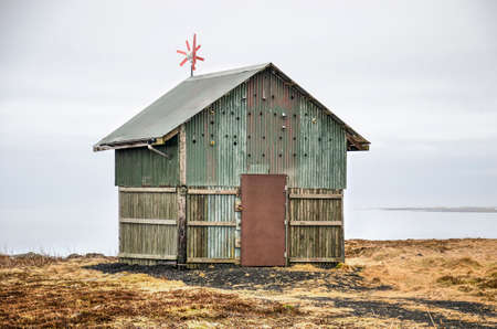 Keflavik, Iceland, March 1, 2019: Little green cabin made of wood and corrugated metal in a desolate landscape with the ocean in the backgroundのeditorial素材