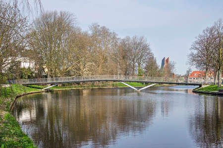 Haarlem, The Netherlands, April 2, 2019: view of the surrounding canal of the ramparts of the old town, crossed by a modern pedestrian bridge and lined with treesのeditorial素材