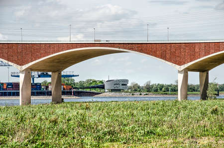 Nijmegen, The Netherlands, April 25, 2019: view across the floodplains under the concrete and brick arches of bridge De OVersteek towards the other bank of the river Waal with the traffic guidance centerのeditorial素材