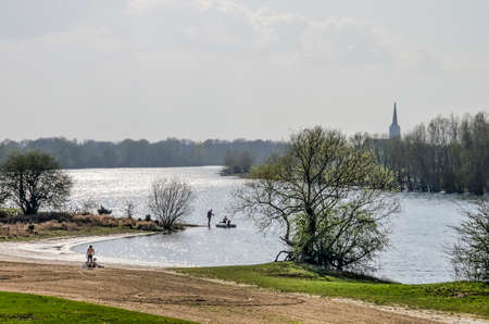 Doesburg, The Netherlands, March 30, 2019: people recreating on a beach along a closed-off section of the IJssel river on a sunny day in springtimeのeditorial素材