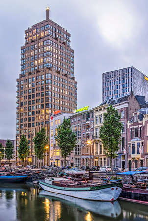 Rotterdam, The Netherlands, May 21, 2019: Wijnhaven harbour at dusk, with the recent Wijnhaeve apartment tower, reconstructed canal houses and historic bargesのeditorial素材