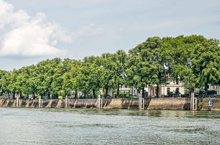 Deventer, The Netherlands, June 18, 2019: a high brick quay wall and large trees at the city's waterfront on the river IJsselのeditorial素材