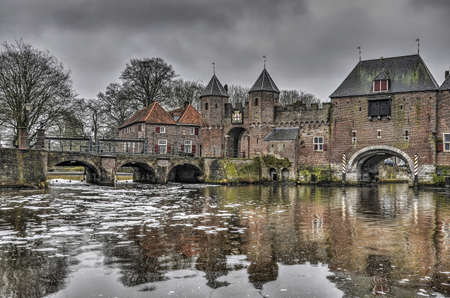 Amersfoort, The Netherlands, February 26, 2017: 14th century Koppelpoort across the river Eem and an adjacent bridge across the Beek on a grey day in winterのeditorial素材