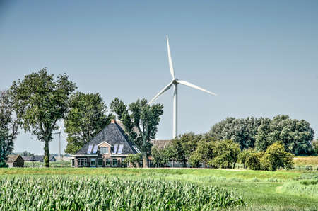 Franeker, The Netherlands, July 27, 2019: Frisian polder landscape with a traditional farm, modern...