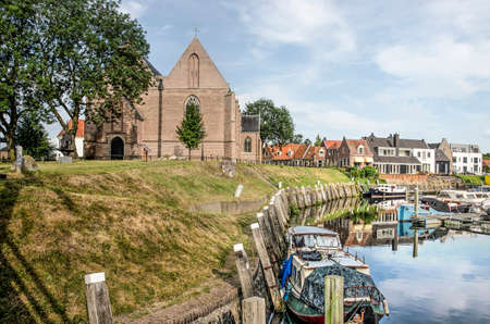 Vollenhove, The Netherlands, August 4, 2019: picturesque scene with boats in the old harbour and the west facade of Saint Nicholas churchのeditorial素材
