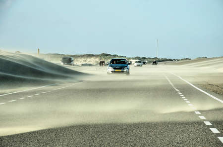 Brouwersdam, The Netherlands, August 10, 2019: a strong wind on a summer day blows sand from the beach and dunes onto the roadのeditorial素材