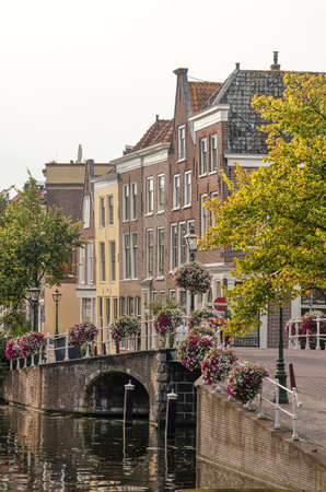 Leiden, The Netherlands, September 3, 2019: autumn scene along New Rhine canal with historic houses, a brick arch bridge and colorizing treesのeditorial素材