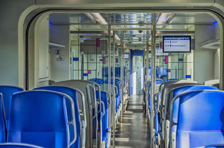 Hoorn, The Netherlands, September 13, 2019: blue seats, reflective ceiling and mondianesque partition walls in the interior of a new Dutch sprinter trainのeditorial素材