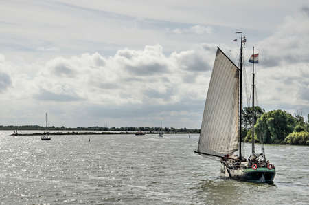 Medemblik, The Netherlands, September 13, 2019: historic sailing boat on lake IJsselmeer, approaching the town's harbour on a sunny day in late summerのeditorial素材
