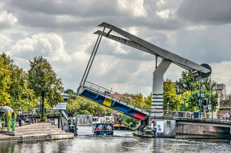 Haarlem, The Netherlands, September 9, 2019: Langebrug (Long Bridge) across the Spaarne river opens for a small yacht to pass on a cloudy day in early autumnのeditorial素材