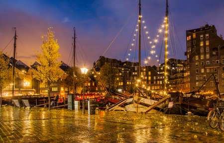 Rotterdam, The Netherlands, November 13, 2019: view from the quay towards the Old Harbour with historic bargs and modern architecture on a rainy evening in the blue hourのeditorial素材