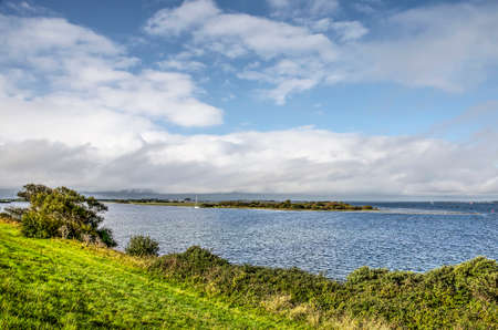View from the dike towards former estuary, now lake, Grevelingen, dotted with island, under a partly blue sky on a day in autumnのeditorial素材