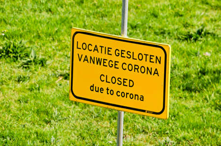 Rotterdam, The Netherlands, April 8, 2020: green lawn with yellow sign stating in Dutch and English:...