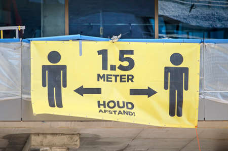 Rotterdam, The Netherlands, April 22, 2020: large yellow sign at construction site encouraging workers to keep 1,5 meter distance to prevent spread of covid-19のeditorial素材