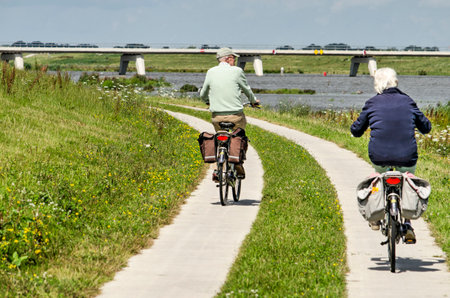 Kampen, The Netherlands, July 27, 2020: elderly couple bicycling on a concrete path along the new Reevediep river channelのeditorial素材