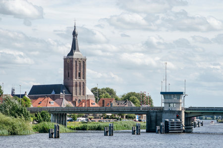 Hasselt, The Netherlands, August 2, 2020: view of the town's waterfront from the other side of Zwartewater river, with the 14th century church and the bridge, under a cloudy skyのeditorial素材
