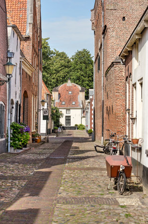 Elburg, The Netherlands, July 30, 2020: bicycles, brick and plaster houses and cobblestone pavement in a narrow street in the old fortified townのeditorial素材