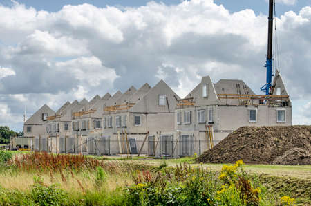 Numansdorp, The Netherlands, July 10, 2020: construction site of a row of terrace houses, with prefab concrete walls awaiting finishing under a dramatic skyのeditorial素材