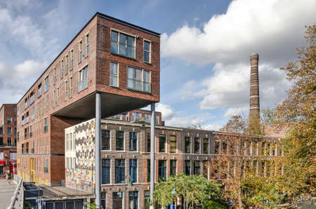 Delft, The Netherlands, October 4, 2020: Modern brick housing block partially build over a row of...