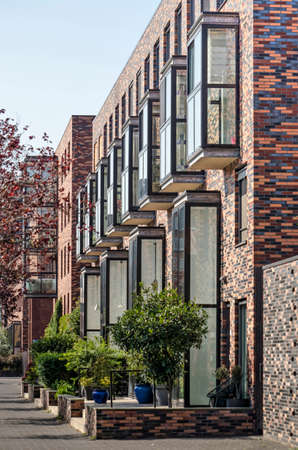 Rotterdam, The Netherlands, September 19, 2020: row of modern townhouses at Kop van Zuid neighborhood with loggias and facades with varied blend of bricksのeditorial素材