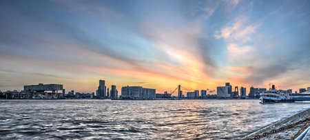 Rotterdam, The Netherlands, February 12, 2016: the river Nieuwe Maas, with the center of Rotterdam in the distance, under a spectacular sky at sunsetの写真素材