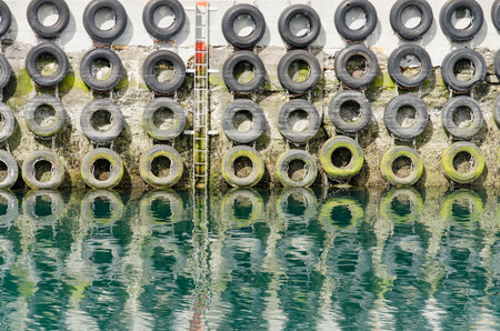 Old car tires for protection of the hull of mooring ships, and an emergency ladder attached to a...