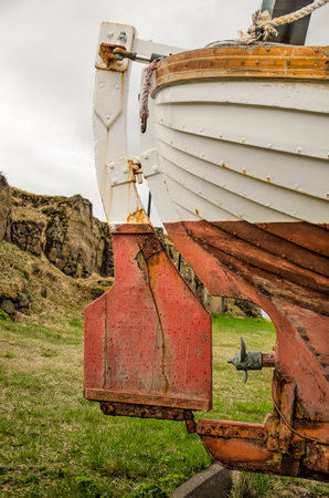 Stern and rudder of a small, old, wooden boat, with rust stains and other damageの写真素材