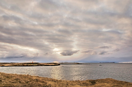 The sun approaching the horizon behind the clouds over BreiÃ°afjÃ¶rÃ°ur in Iceland, as seen...