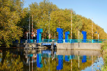 Gouda, The Netherlands, November 3, 2024: bridge across treelined Breevaart canal on a sunny day in...