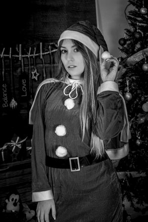 young woman dressed in red with the costume of mama noel, at christmas in front of a christmas tree holding the hat.- christmas.- partiesの写真素材