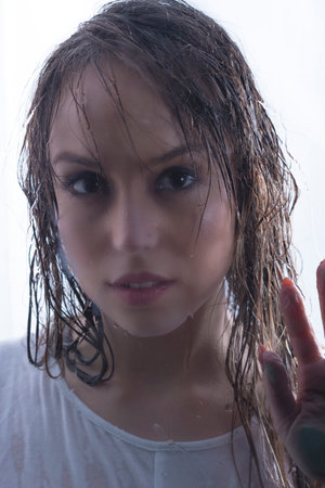 beautiful young woman with long hair wet from shower dressed in white t-shirt mischievously looking...