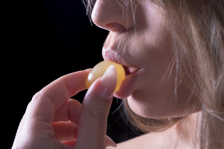 portrait young woman putting a yellow grape on her full lips sexually portrait of woman and foodの写真素材