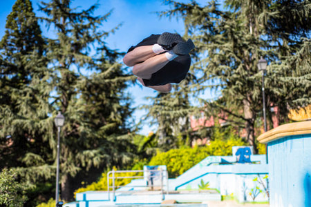 young male athlete doing parkour jumps and acrobatic exercises in the urban area of...