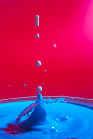 collision of moving water drops of blue color on a purple red background forming figures and waves when falling and colliding with each other photography and high resolution images relaxation photographyの写真素材