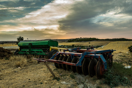 abandoned farmer's machinery dumped in the field at sunset