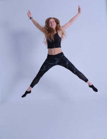 blonde young woman with long hair smiling happy jumping with legs and arms open hair forming figures photography of happinessの写真素材