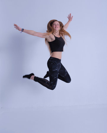 blonde woman with long hair jumping happy smiling with raised hands photography of happinessの写真素材