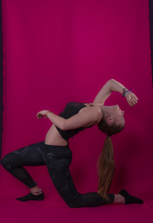 woman with long blonde hair performing a backwards bending yoga pose image with purple background photography happinessの写真素材