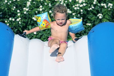 a toddler in armbands coming down a waterslide