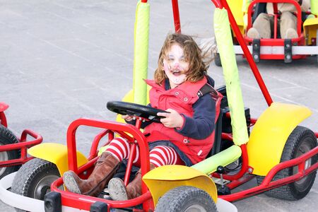 a caucasian girl on a go-kart having lots of fun with her face paintedの写真素材