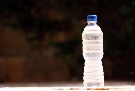 a cold bottle of water with condensation on the bottle against a natural backgroundの写真素材