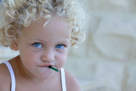 young caucasian child with a dangerous small object in her mouth which is a choking hazardの写真素材