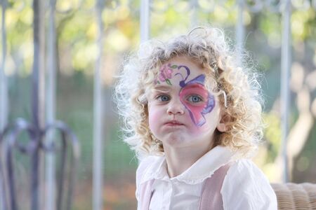 portrait of an expressive young caucasian child with her face painted