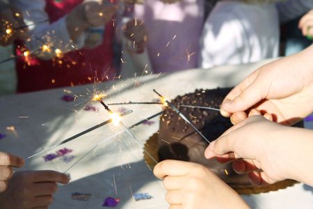 little hands round a birthday cake lighting sparklers to celebrateの写真素材