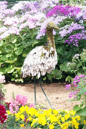 a metal structure in the shape of an ostrich to depict ostrich farming decorated with weeds and flowersの写真素材
