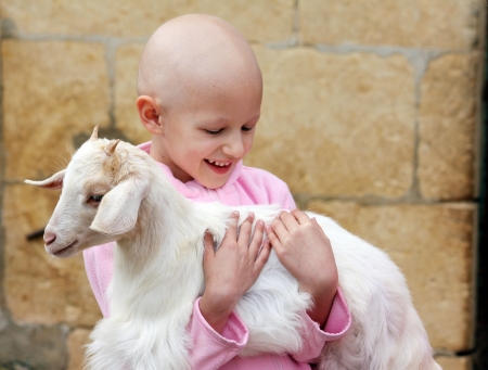 child with cancer carrying a goatの写真素材
