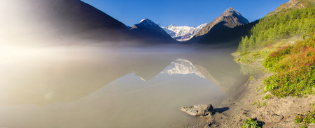 Misty mountain lake surrounded by high peaksの写真素材
