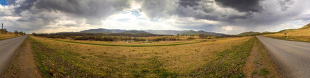 Panorama of the hills, paved road and cyclist